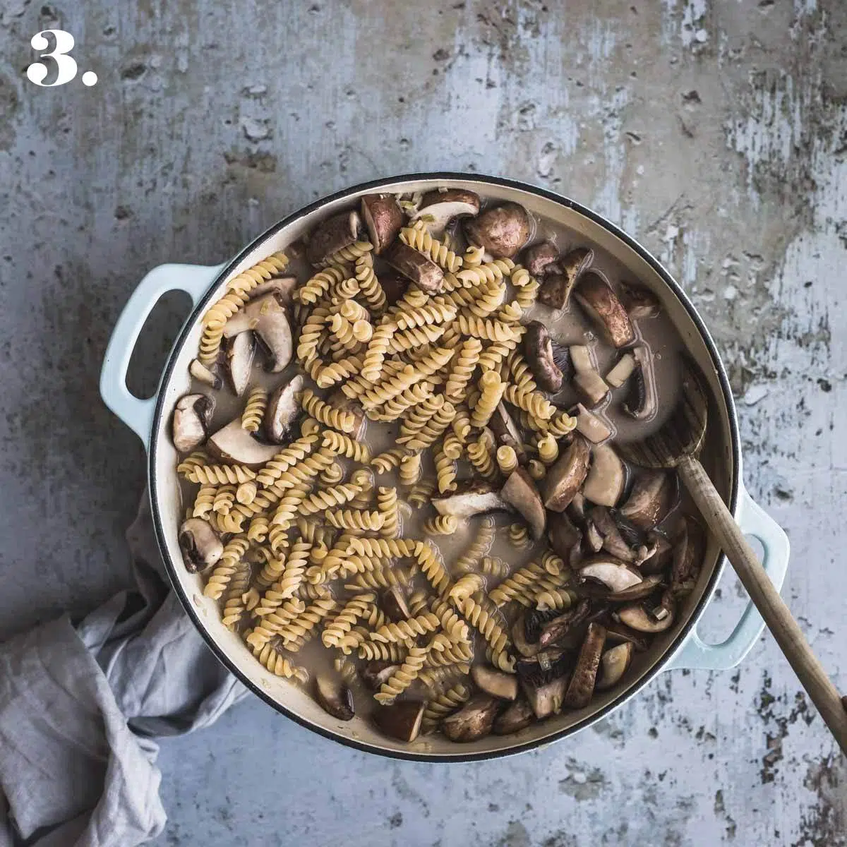 Mushrooms and pasta cooking in a large pot. 