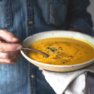 A man holding a bowl of pumpkin soup.