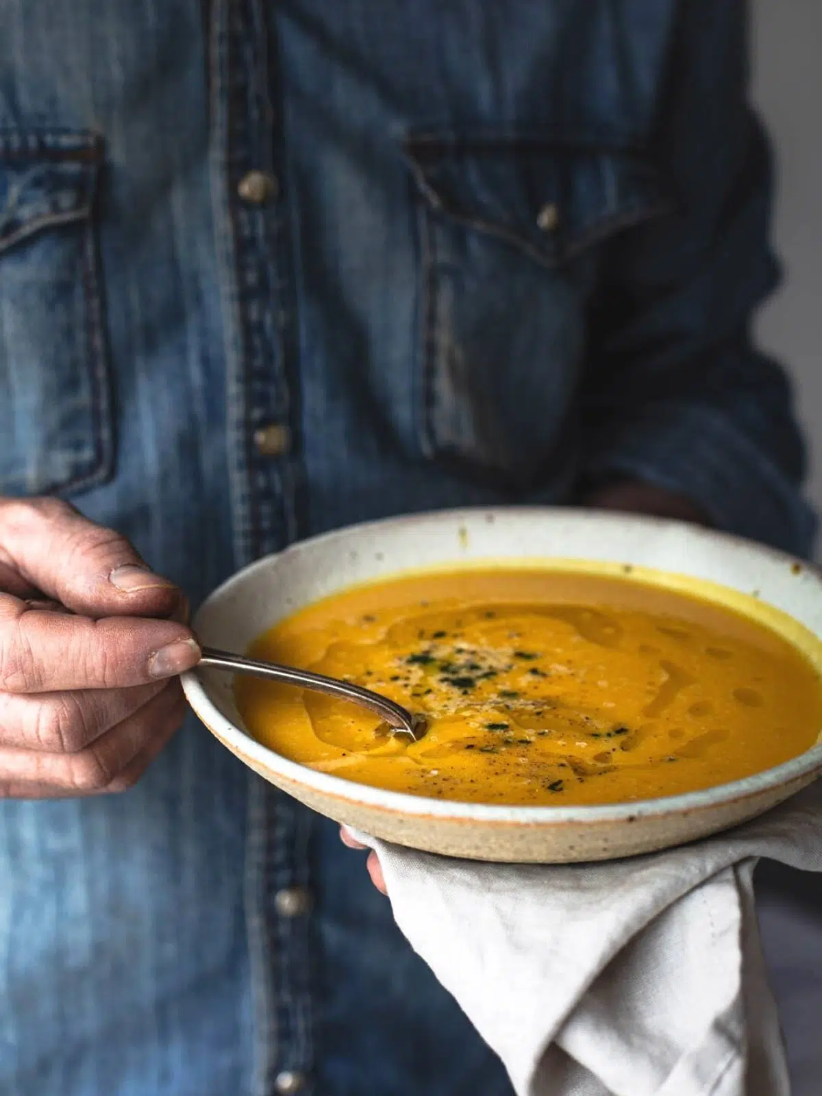 A man holding a bowl of pumpkin soup.