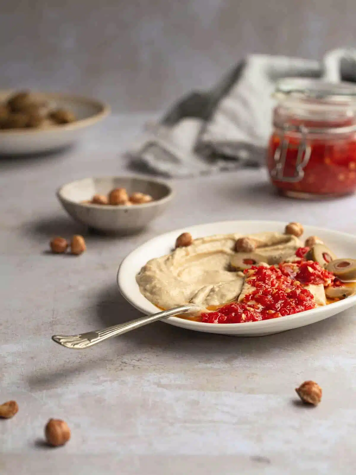 Hummus, olives and chilli sauce on a plate.