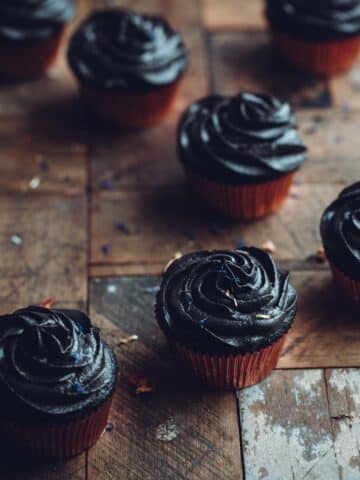 Black cupcakes on a rustic wooden table.