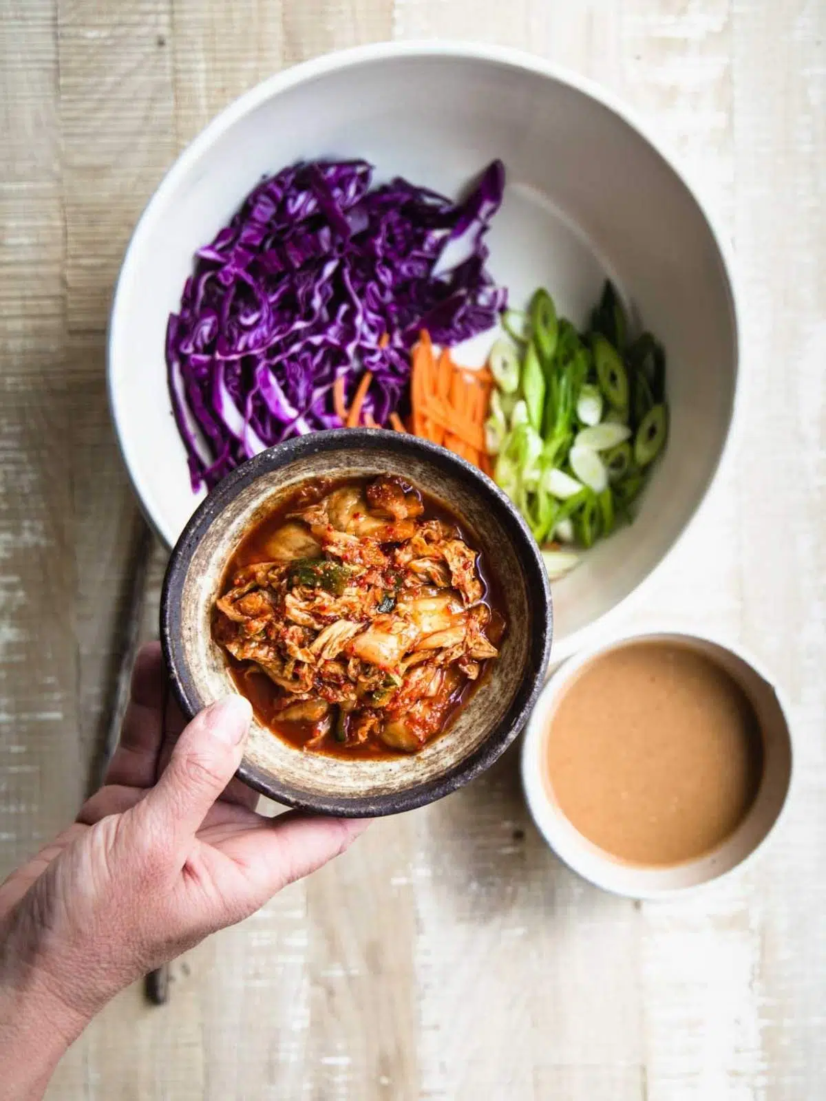 Kimchi and vegetables in a bowl with salad dressing. 