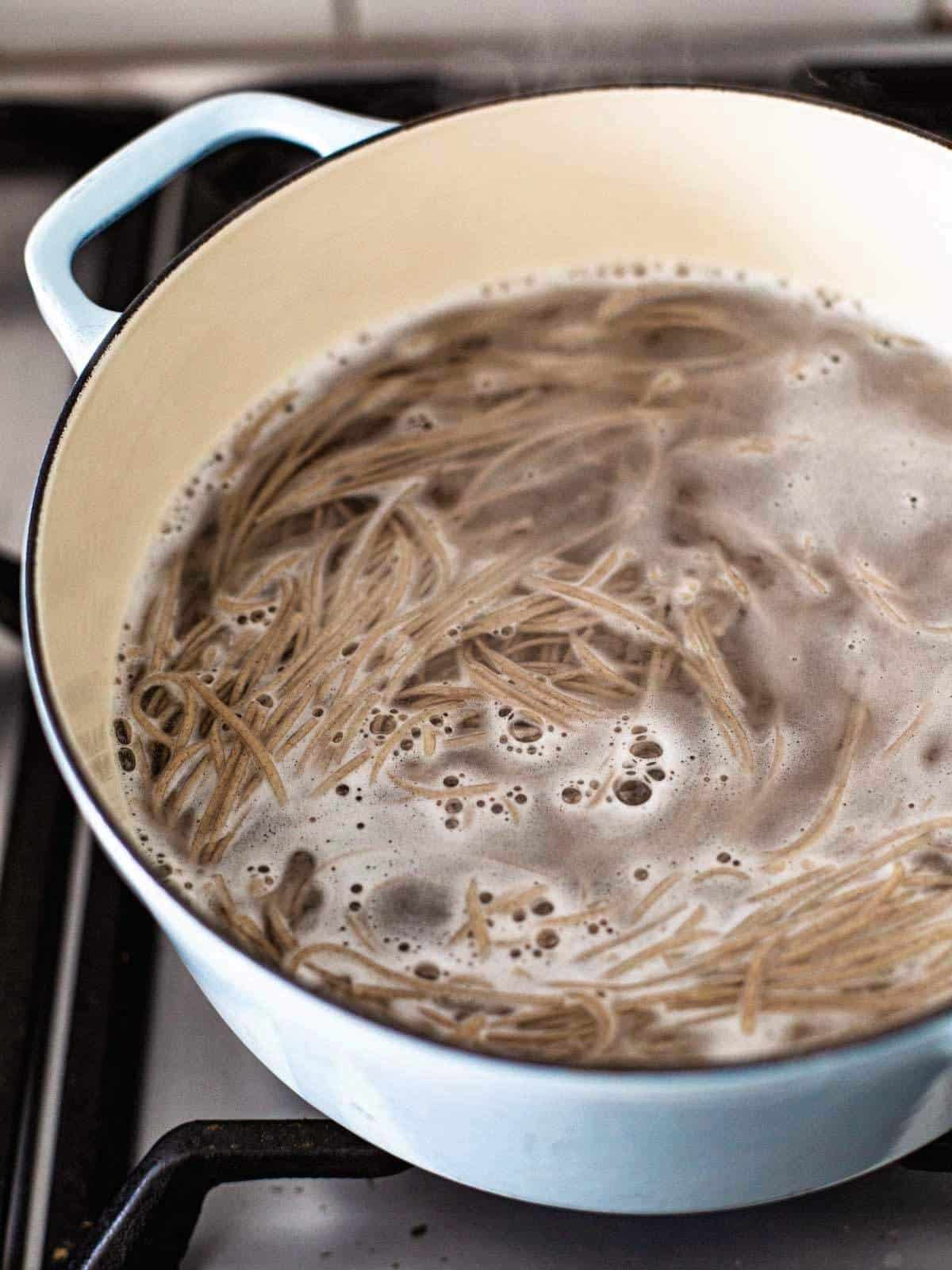 Soba noodles cooking in a pot.