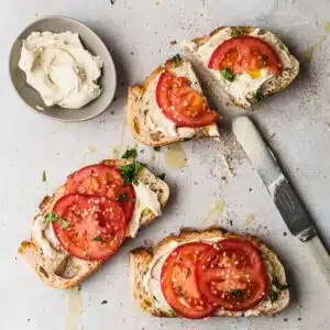 Cashew ricotta in a dish with toast and tomatoes.