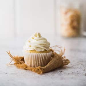 A cupcake with coconut buttercream on a white background.
