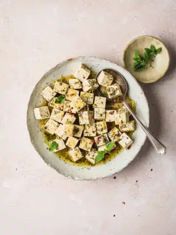 A bowl of tofu feta with chilli and herbs.