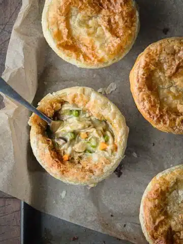 Pot pies on a rustic tray with one showing the filling.