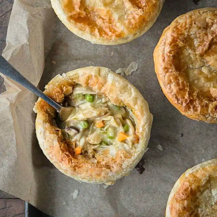 Pot pies on a rustic tray with one showing the filling.