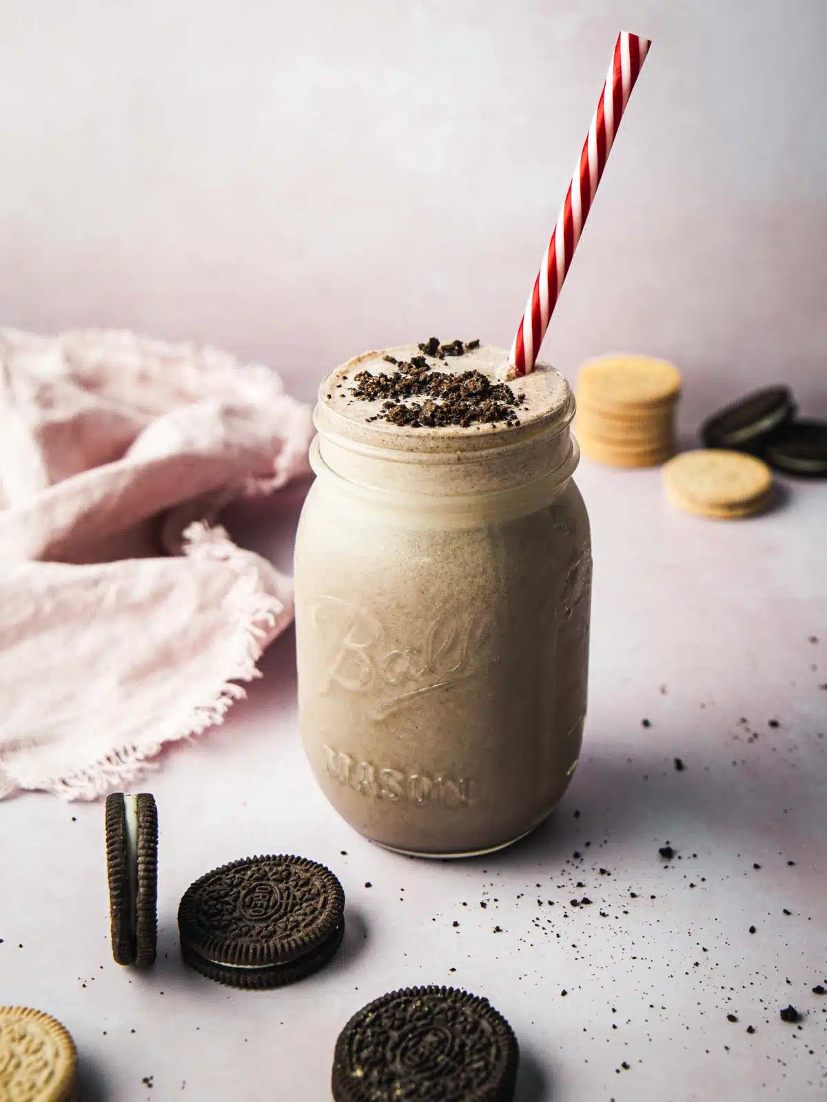 A single jar full of smoothie with Oreos cookies around.