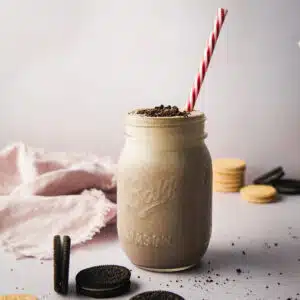 A jar of smoothie with Oreos cookies around.