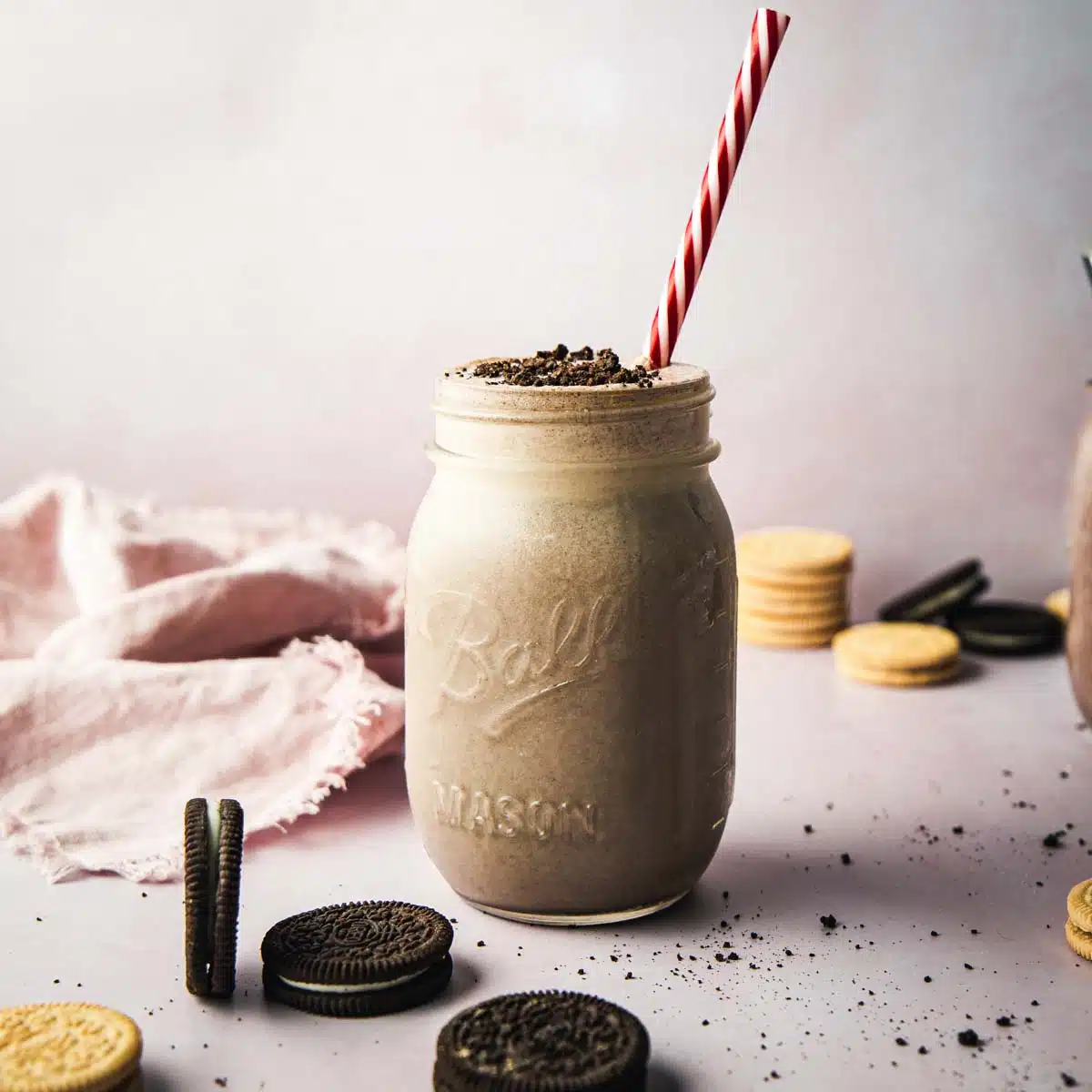 A jar of smoothie with Oreos cookies around.