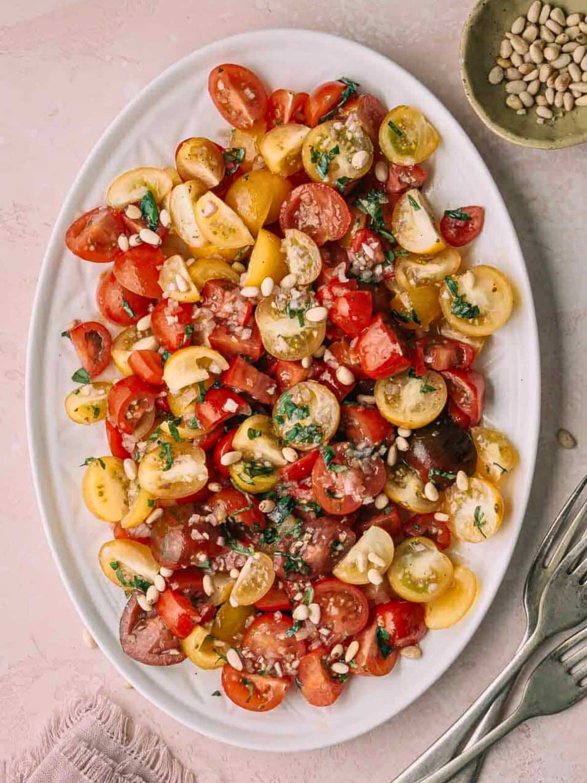 An oval plate with tomatoes and pine nuts.