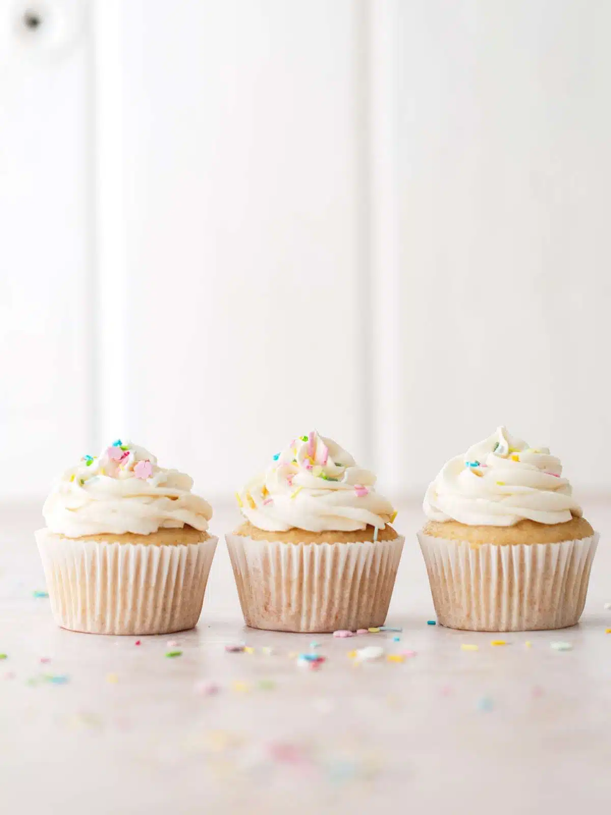 Three vanilla cupcakes with frosting.