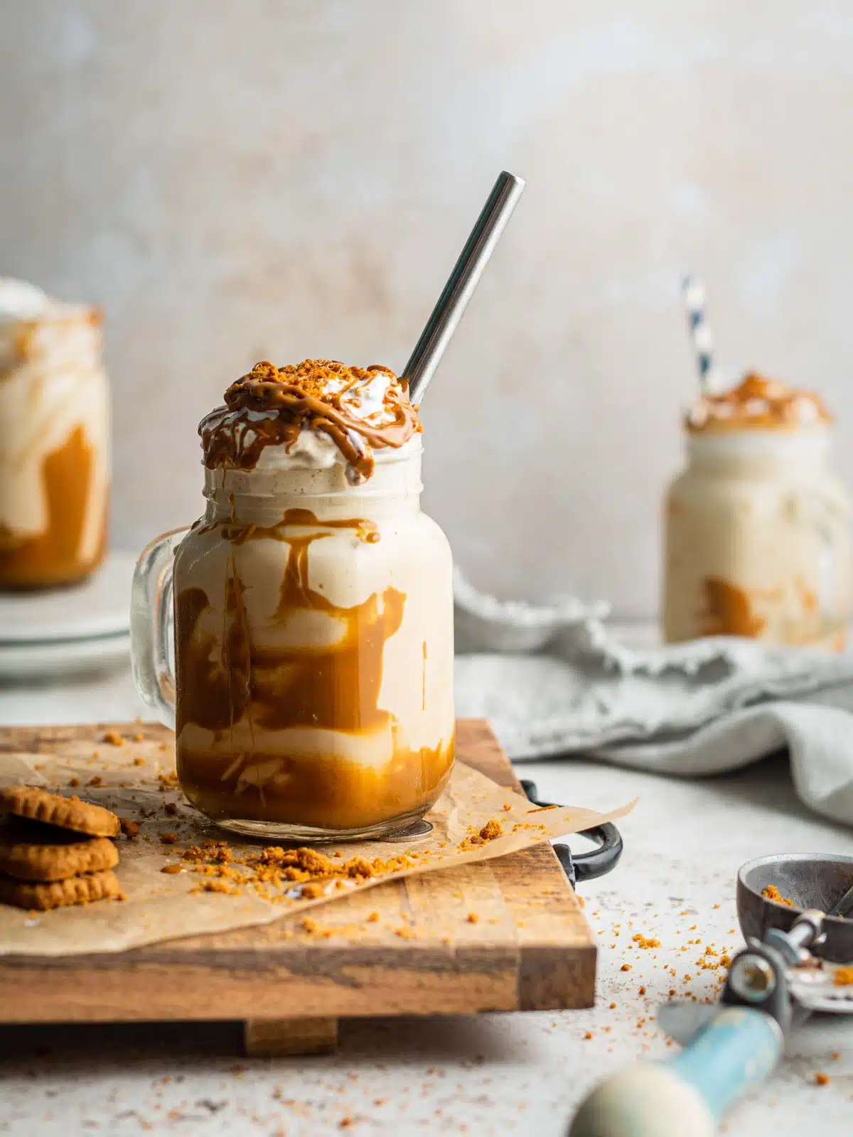 Three milkshakes with cream on a table.