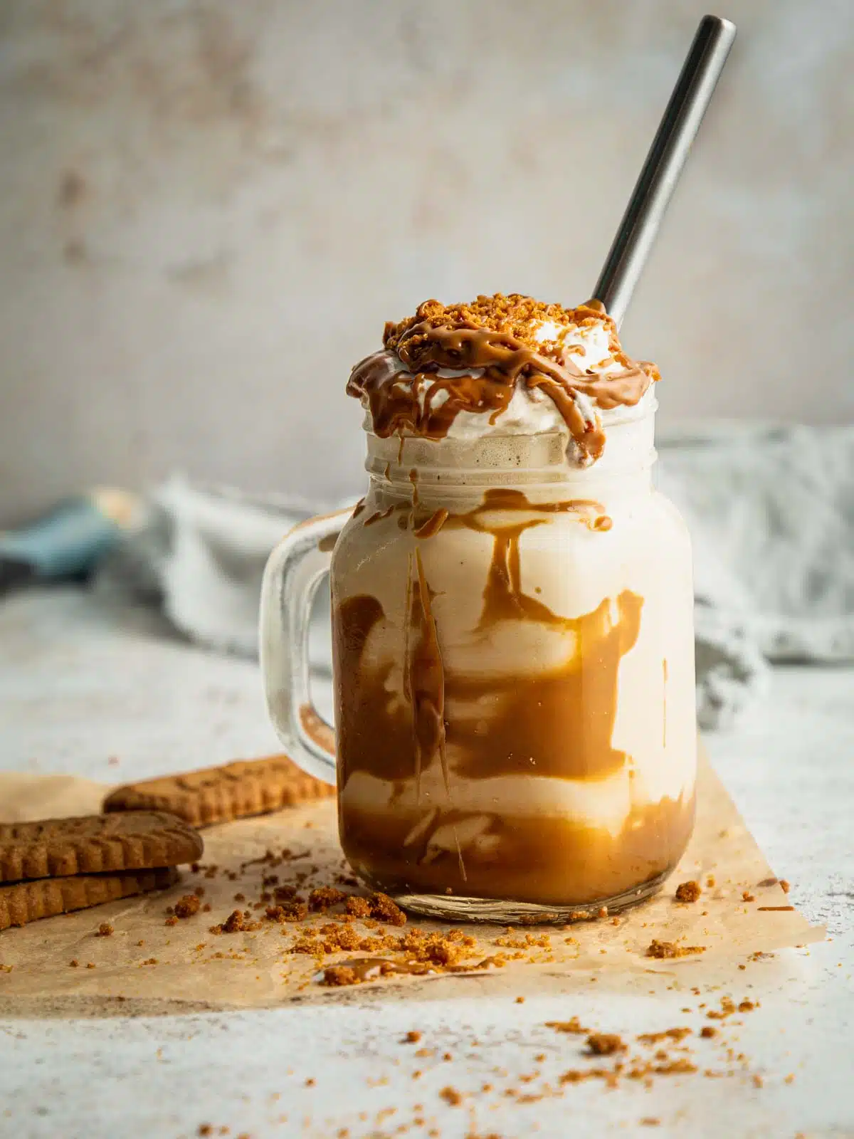 A Biscoff Milkshake with cream and topping on a table.