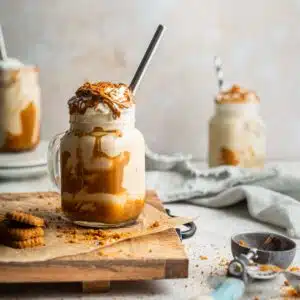 Three milkshakes with cream on a table.