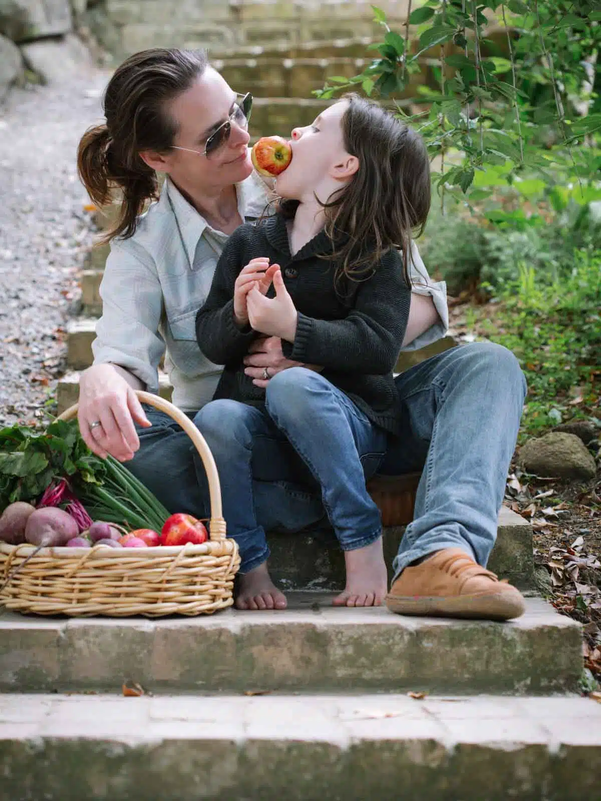 A woman and a child sitting on a step with food.