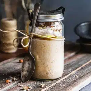 A jar of oats with apple and a spoon.