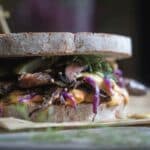 A Reuben sandwich with mushrooms on paper.