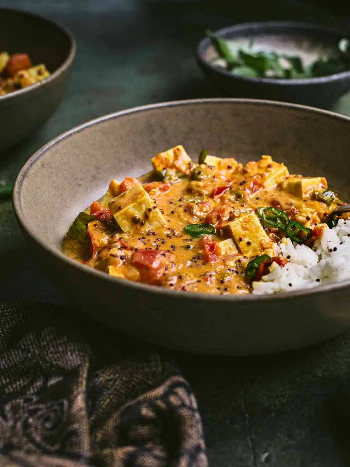 A bowl of tofu curry with rice and greens.