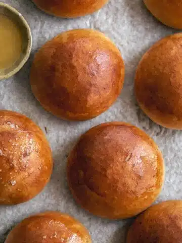 Brioche buns with butter on a tray.