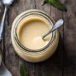 A jar of brandy sauce with a spoon.