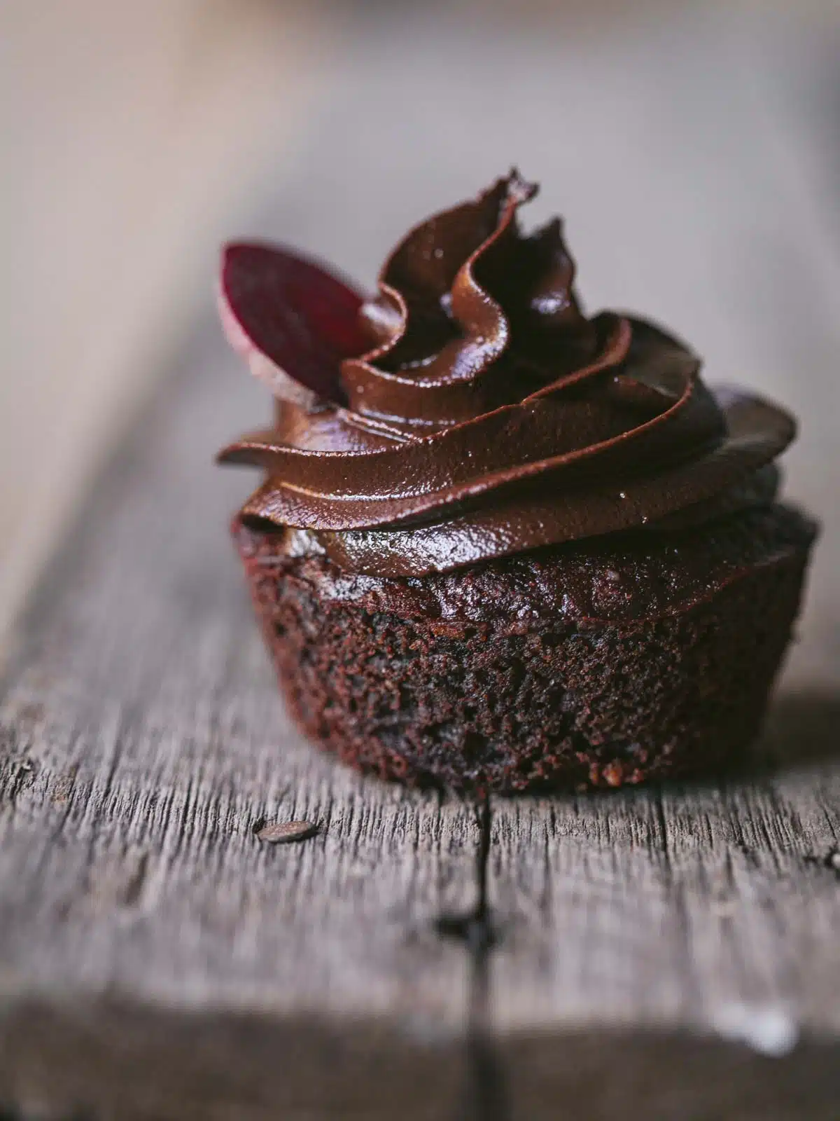 A chocolate cupcake on a wooden board. 