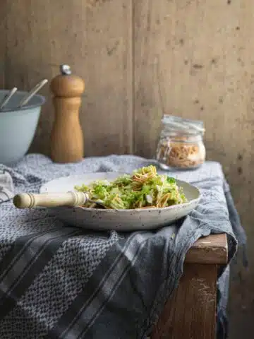 A bowl of cabbage and noodle salad on a rustic table.