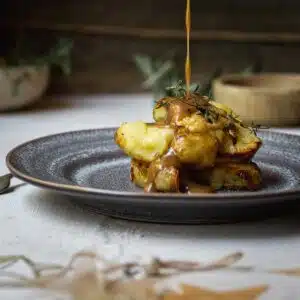 Gravy poured onto roast potatoes.