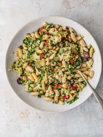 A bowl of salad with white beans.