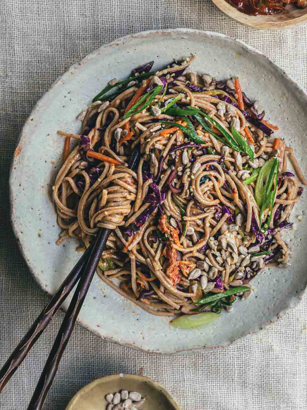 A close up image of kimchi noodle salad with chopsticks.