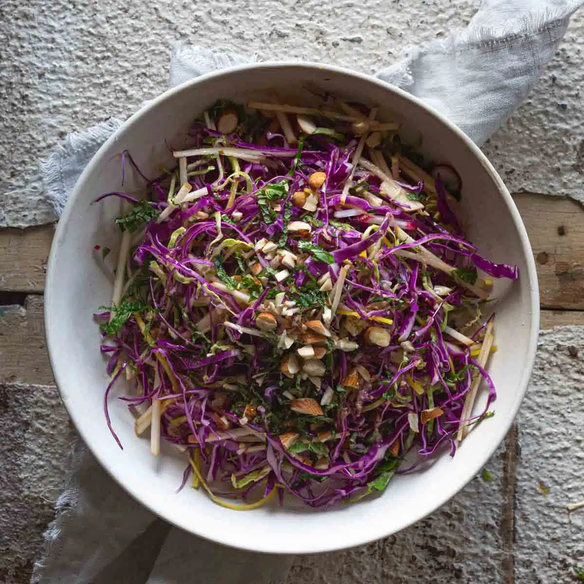 Finely sliced rainbow salad in a white bowl.