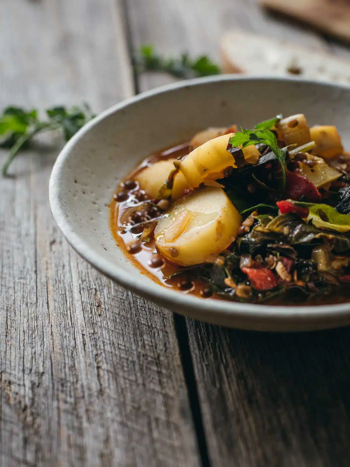 A bowl of stew and potatoes on a wooden table.