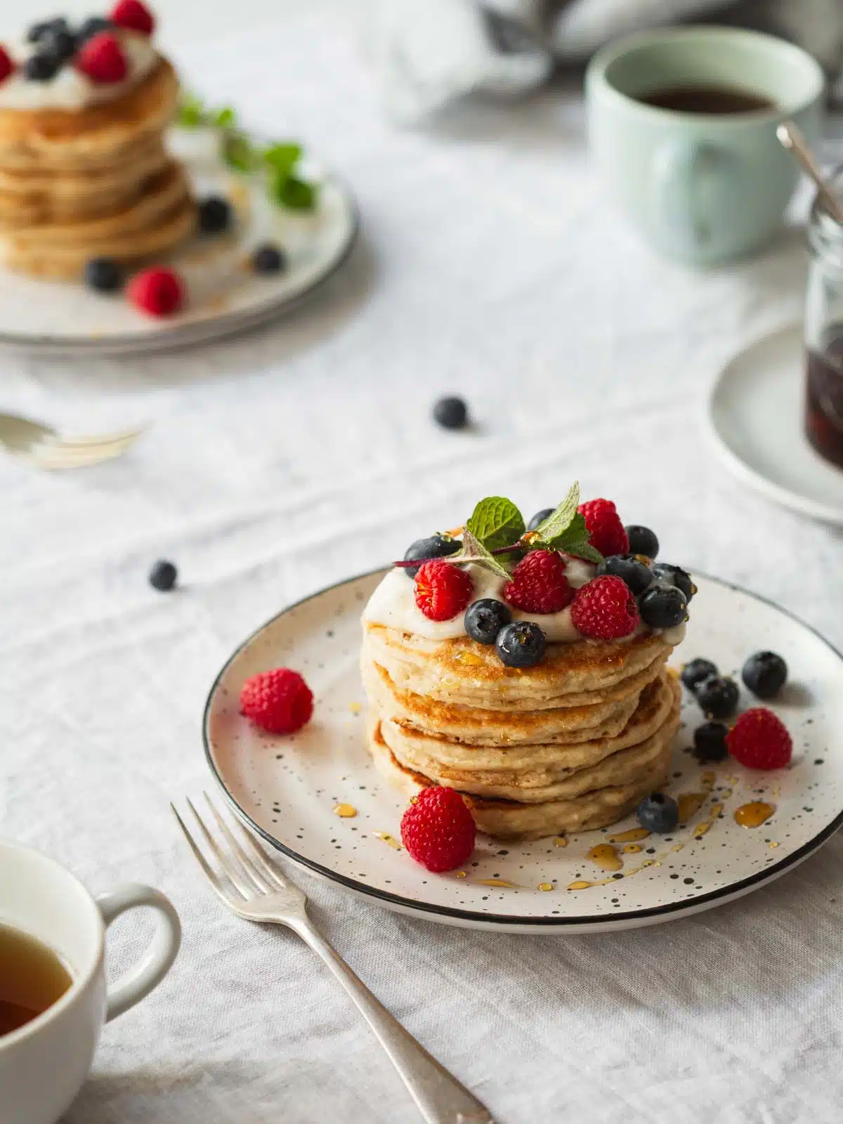 A stack of whole what pancakes and berries at a breakfast setting.