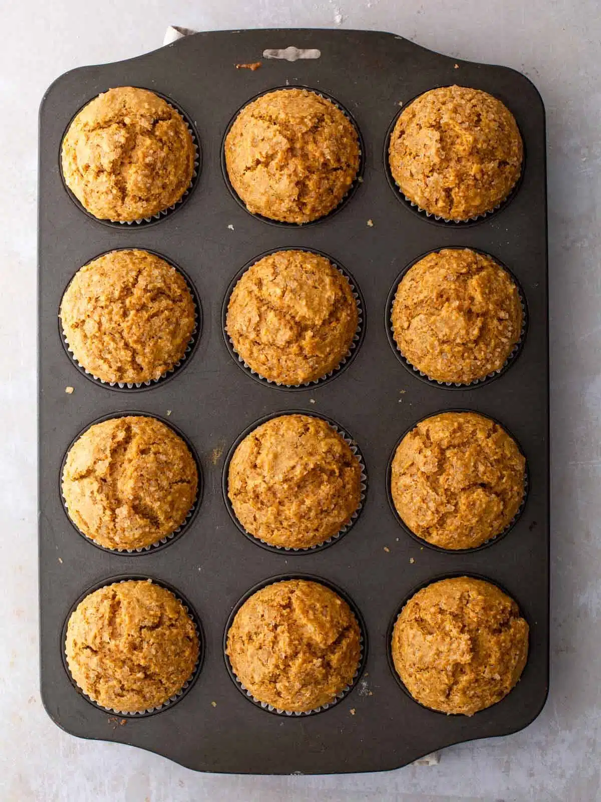 Freshly baked whole wheat pumpkin muffins in a baking tray.