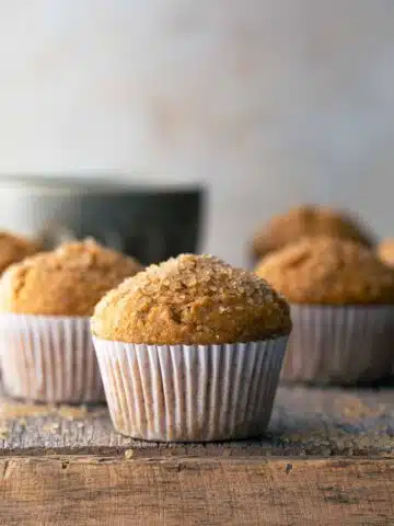 Wholemeal pumpkin muffins on wooden board.