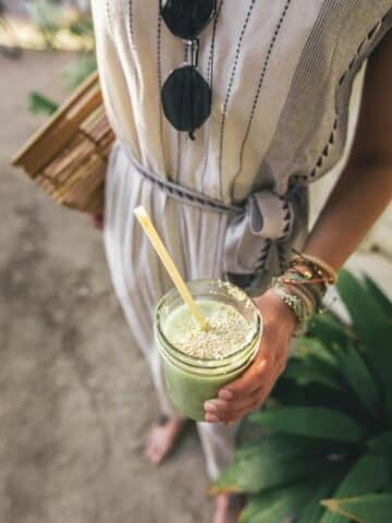 A woman holding a green drink with seeds.
