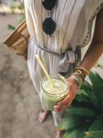 A woman holding a green drink with seeds.