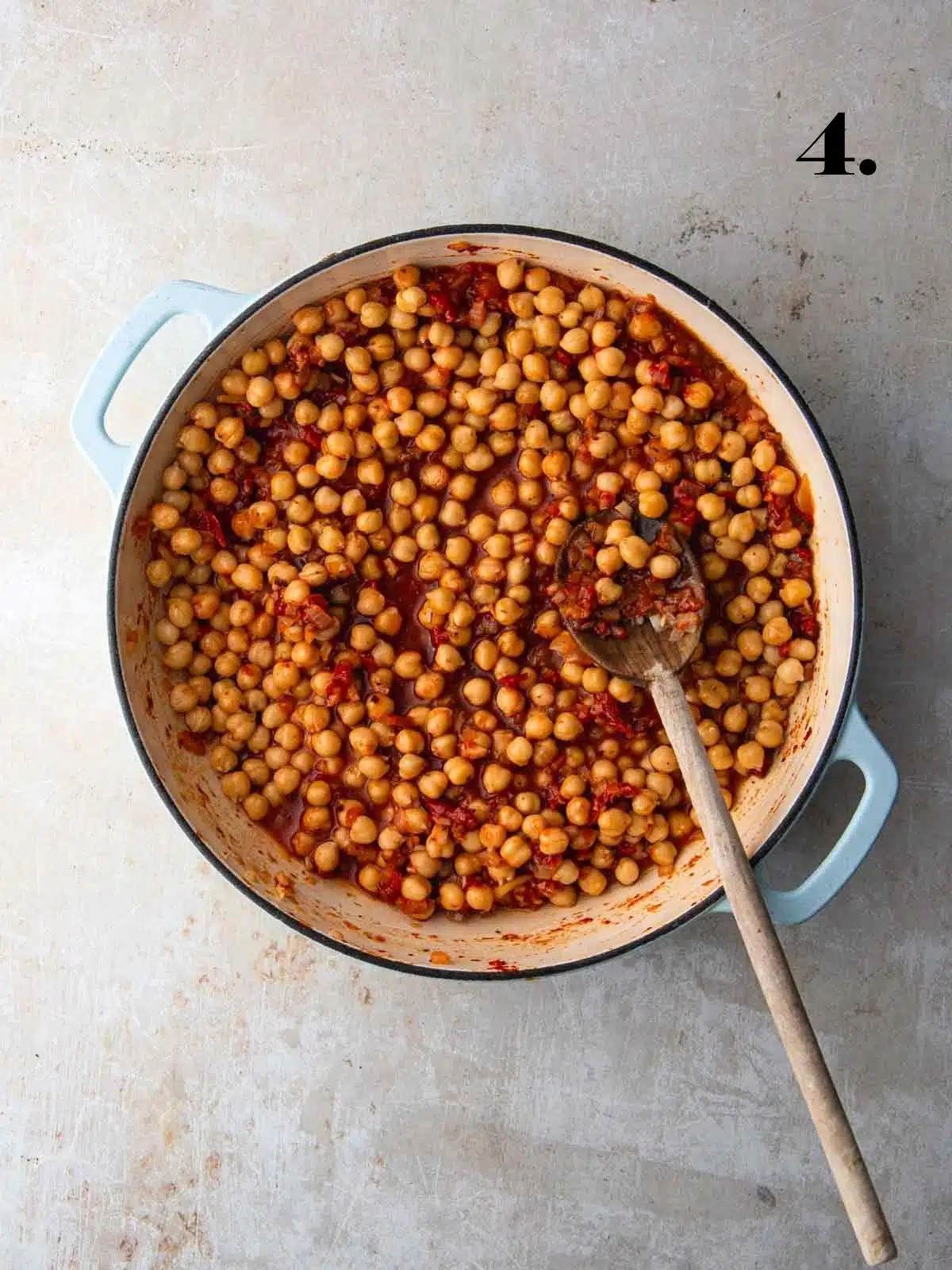 Chickpeas, tomato and stock in a large pan cooking.