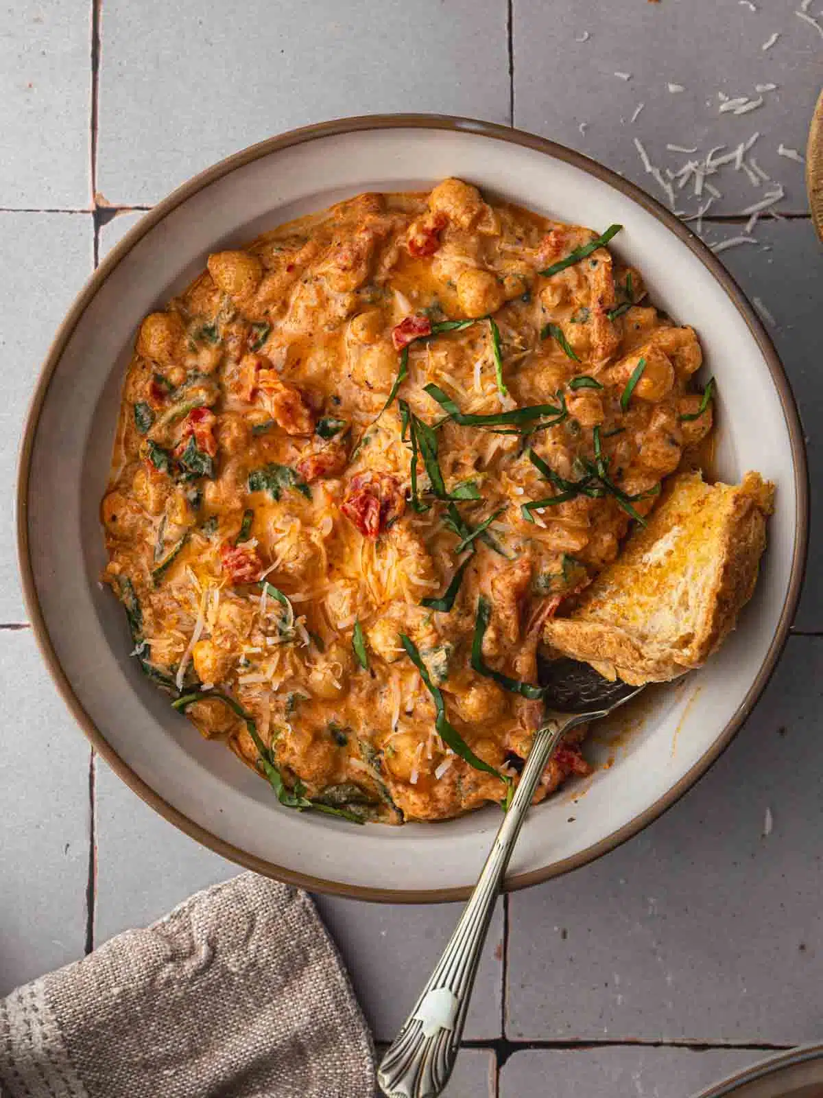 A bowl of creamy Marry Me Chickpeas with fresh basil and a spoon.