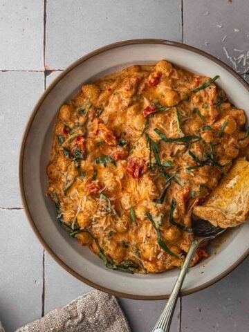 A close up bird's eye view of creamy chickpeas and tomato in a bowl.