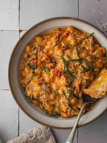 A close up bird's eye view of creamy chickpeas and tomato in a bowl.