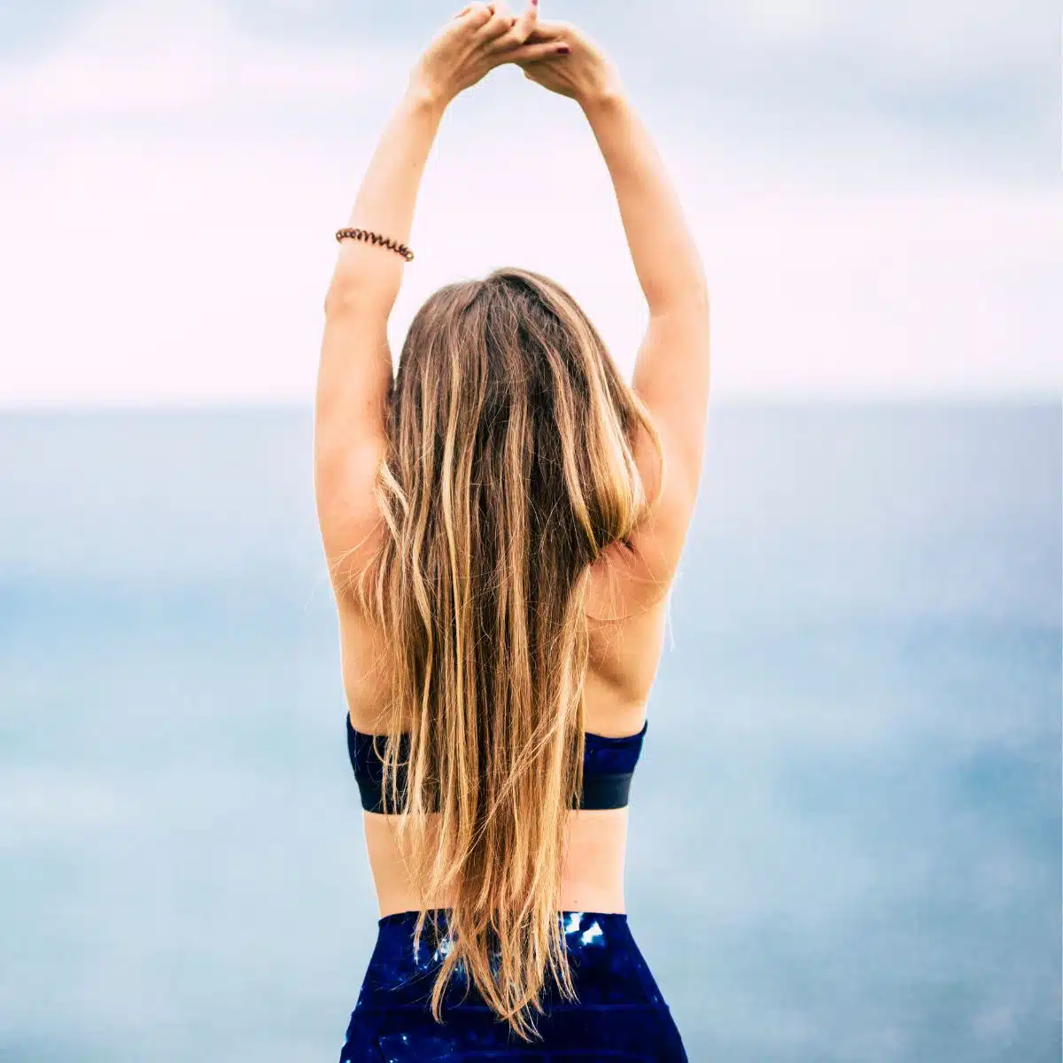 A fit woman in gym wear stretching.