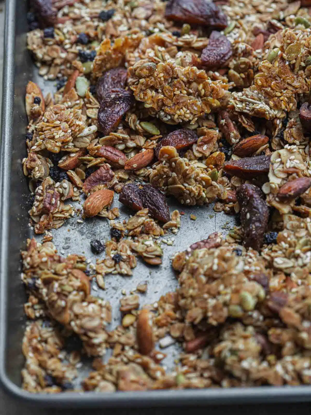 Baked granola broken into pieces in a baking tray.